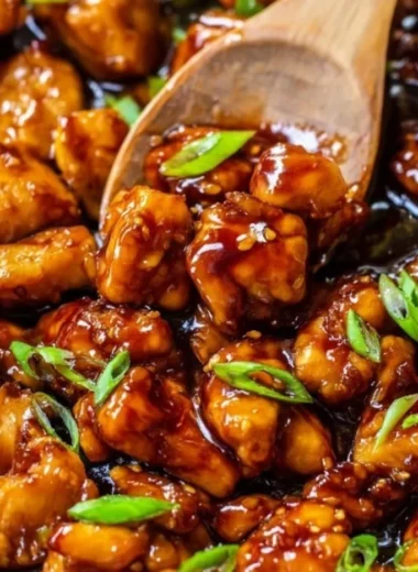 A plated dish of Honey Garlic Chicken garnished with sesame seeds and green onions.