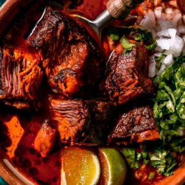 Plate of authentic Mexican Birria served with garnishes and side dishes.