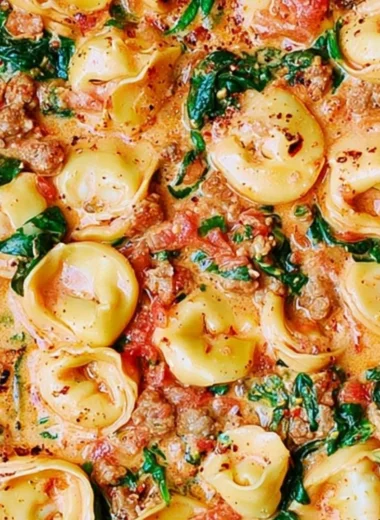 Creamy tortellini with sausage, spinach, tomatoes, and mozzarella served in a bowl.