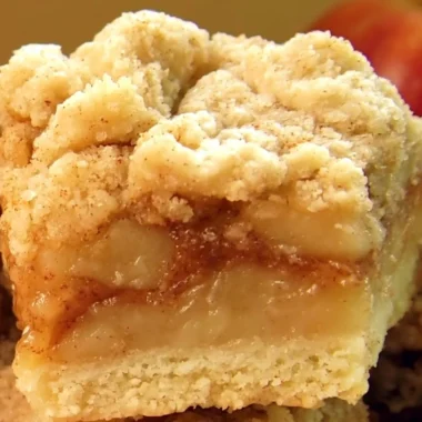 Delicious apple pie bars with streusel topping on a wooden table