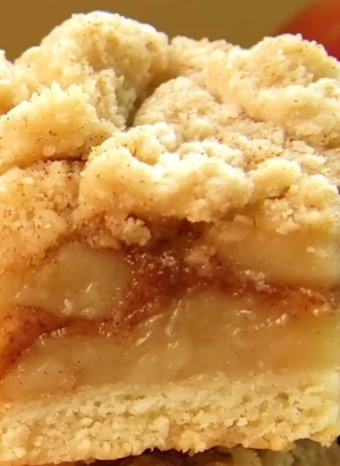 Delicious apple pie bars with streusel topping on a wooden table