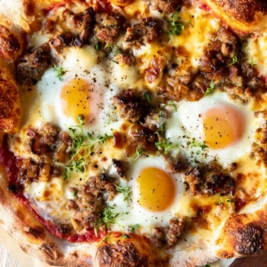 Sausage breakfast pizza topped with eggs and cheese, perfect for brunch.