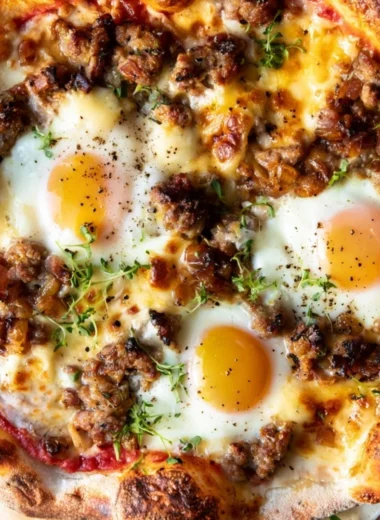 Sausage breakfast pizza topped with eggs and cheese, perfect for brunch.