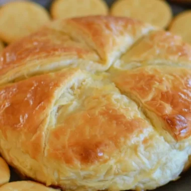 Baked Brie in Puff Pastry served on a rustic wooden platter.