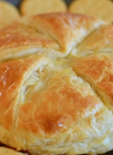 Baked Brie in Puff Pastry served on a rustic wooden platter.