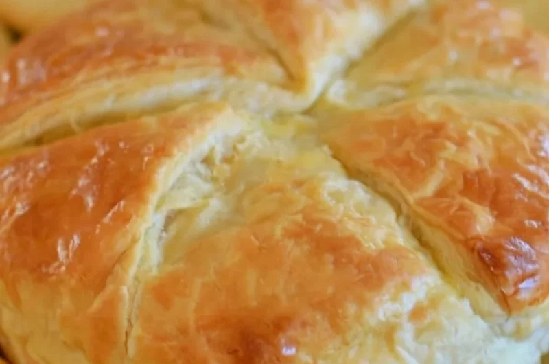 Baked Brie in Puff Pastry served on a rustic wooden platter.