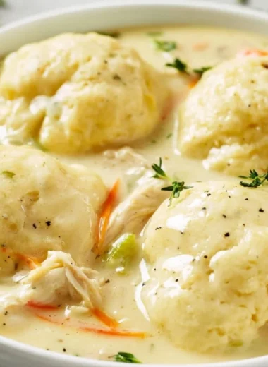 Homemade chicken and dumplings served in a bowl with fresh herbs.