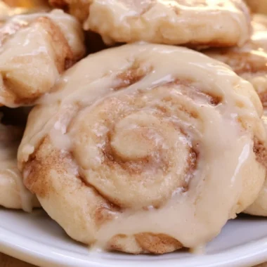 Freshly baked soft cinnamon roll cookies on a cooling rack.
