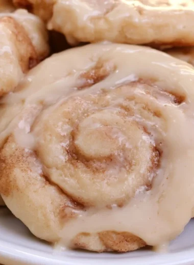Freshly baked soft cinnamon roll cookies on a cooling rack.
