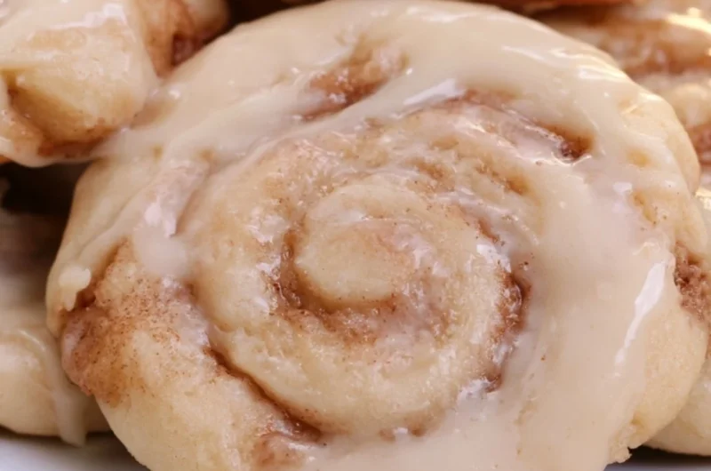 Freshly baked soft cinnamon roll cookies on a cooling rack.